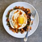 Overhead view of chipotle sweet potato hash with a fried egg and a fork