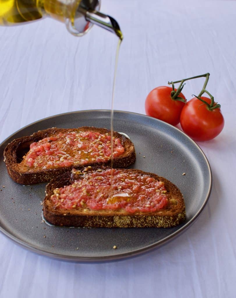 Drizzling olive oil onto bread to make pan con tomate