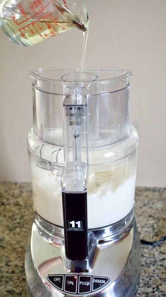 Drizzling oil into food processor with garlic
