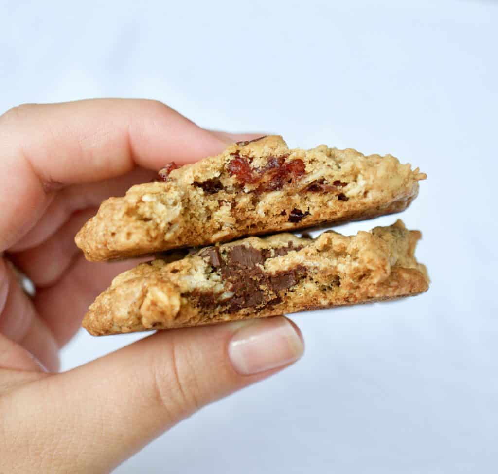 Holding two oatmeal cranberry chocolate chip cookies