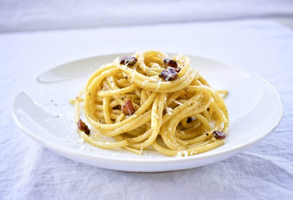 Pasta alla carbonara on a white plate viewed from the front
