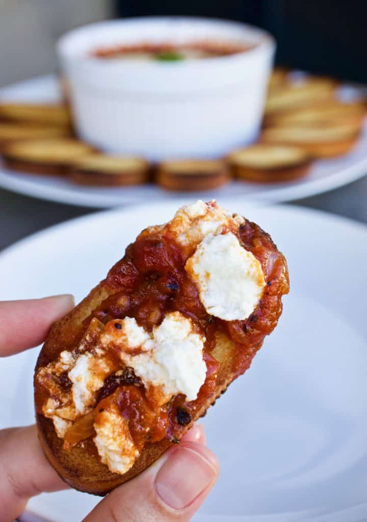 A crostini covered in tomato sauce and goat cheese