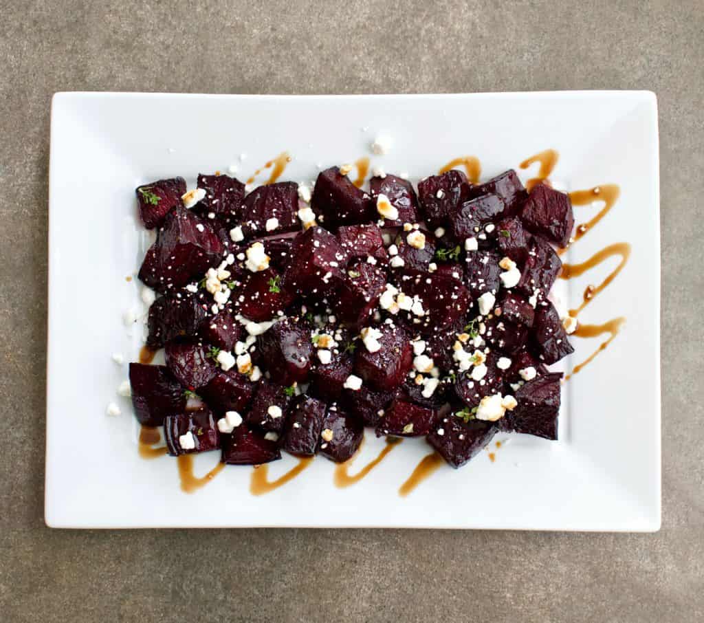 Overhead view of Roasted beets with goat cheese and balsamic reduction on a serving platter