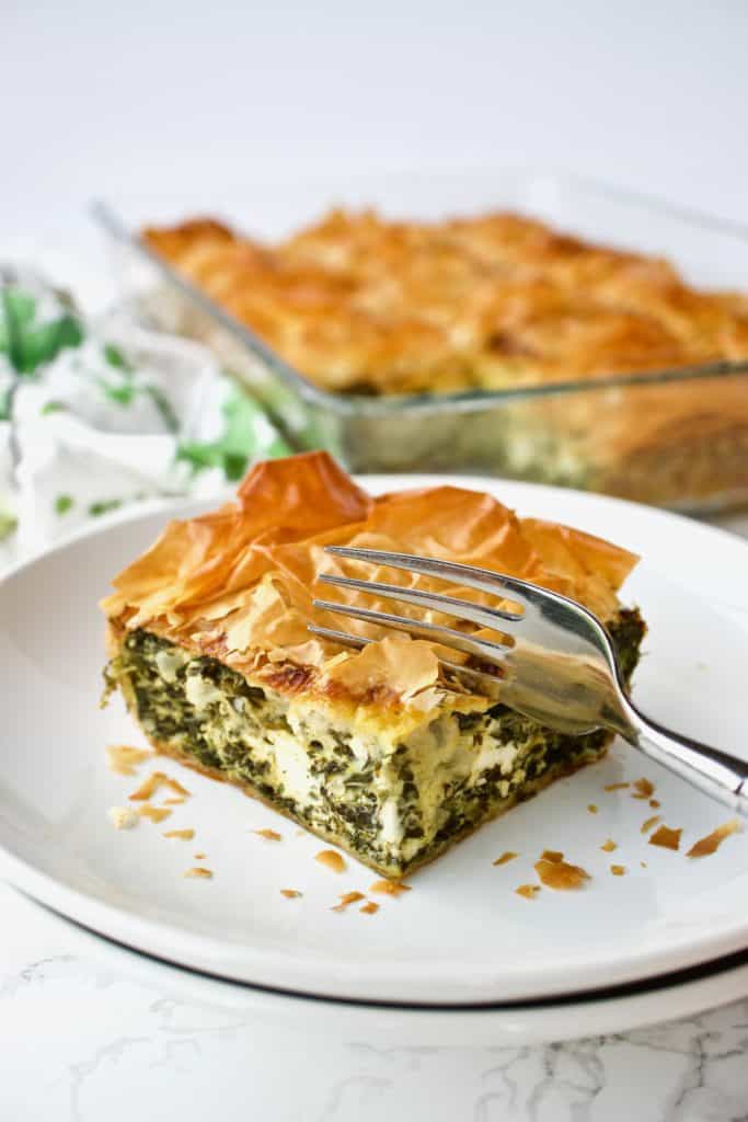 Carving out a piece of spinach pie with a fork