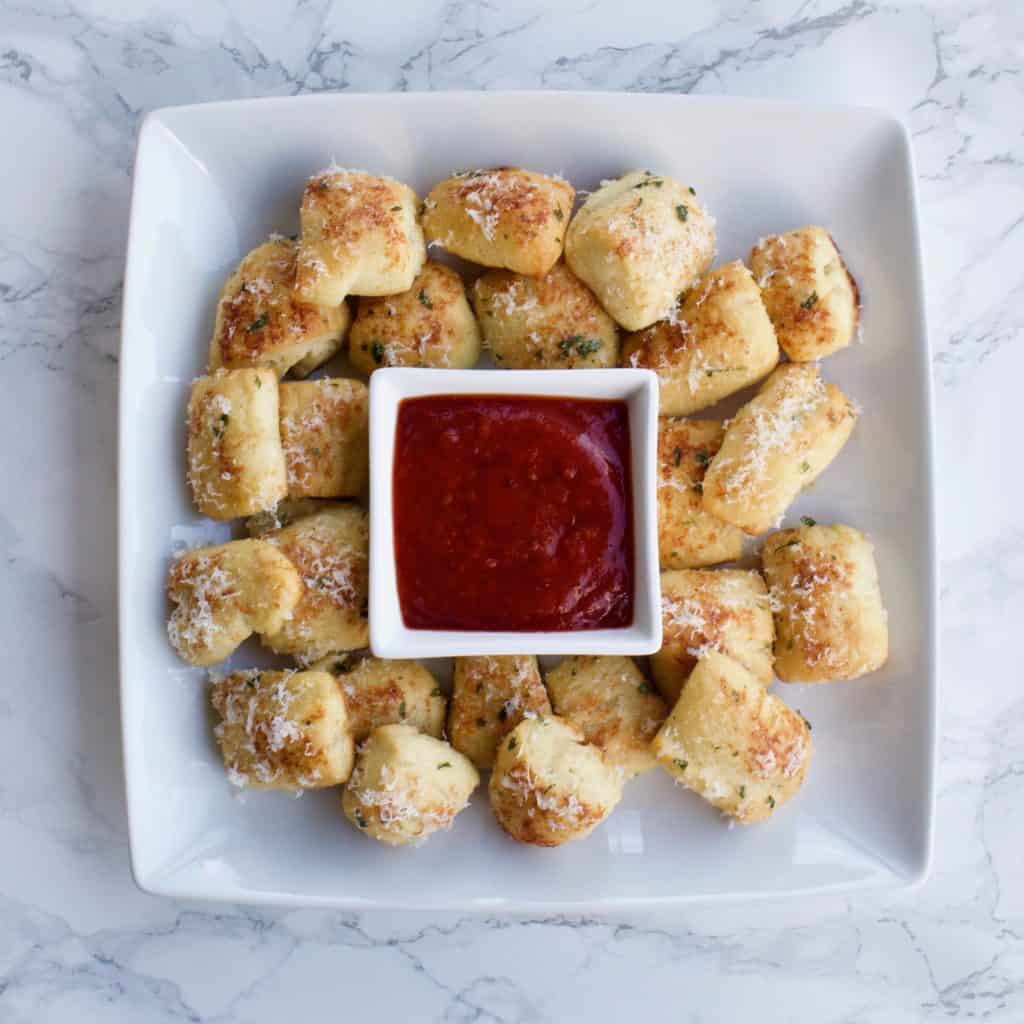 Overhead view of parmesan bread bites with marinara sauce