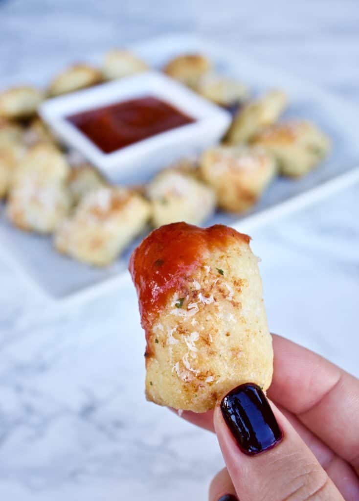 Close up picture of parmesan bread bite dipped in marinara sauce
