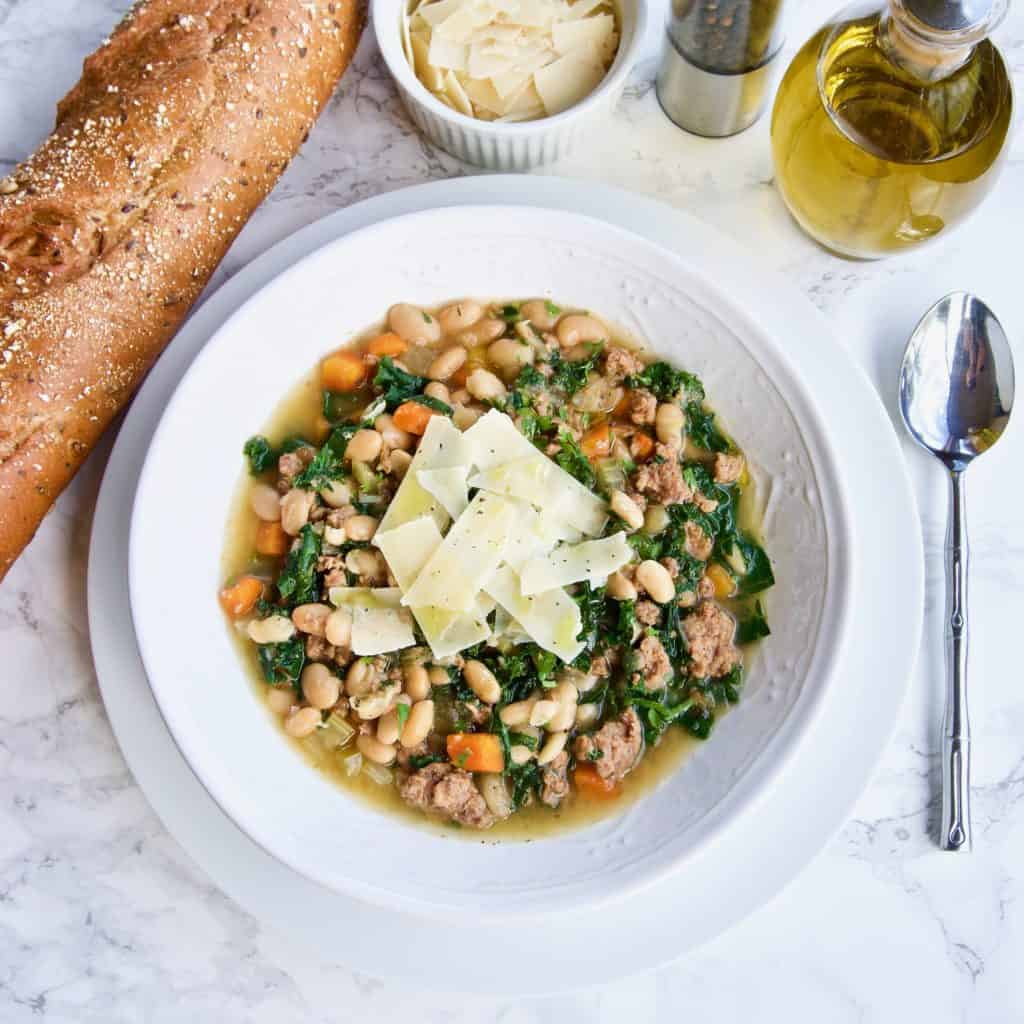 Instant Pot Turkey Sausage, White Bean & Kale Soup in a bowl surrounded by tableware