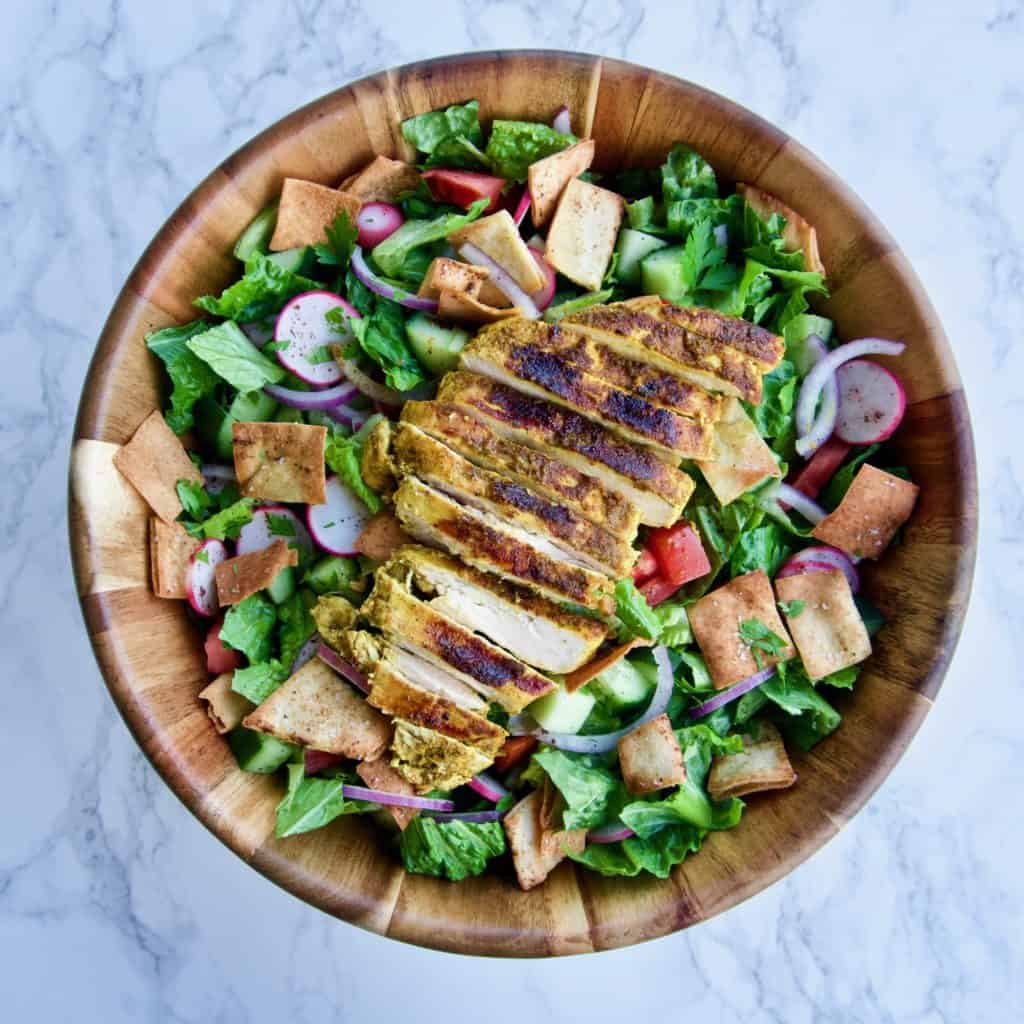 fattoush salad with shawarma-spiced chicken in a wooden bowl