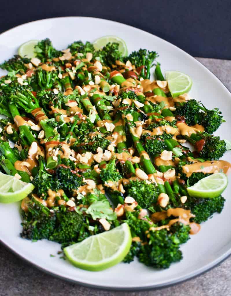 Angled view of roasted broccolini with spicy peanut sauce on a serving platter