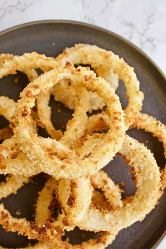 Close up of panko breaded baked onion rings on a gray plate