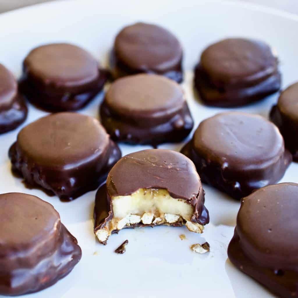 Chocolate peanut butter banana bites on parchment paper. One has a bite taken out of it.