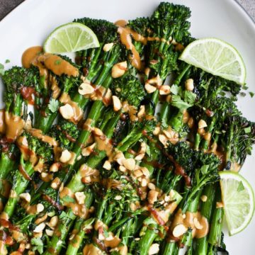 Roasted broccolini with spicy peanut sauce arranged on a plate