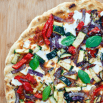 Overhead view of grilled veggie pizza with text banner reading 