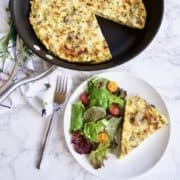 Mushroom and Gruyere frittata on plate next to pan with a slice cut out
