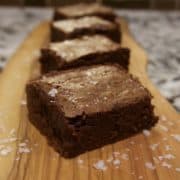 Salted fudge brownies arranged in a line on a wooden board