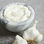 Lebanese Garlic Sauce: Toum in a small bowl surrounded by garlic