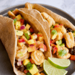 Chipotle Lime Shrimp Tacos on plate with limes and header text at top