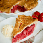 Slice of Strawberry Rhubarb Pie on a white plate with scoop of vanilla ice cream and fork and banner title 