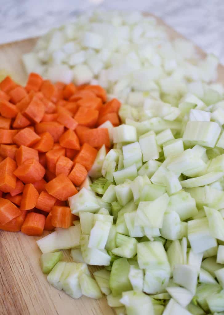 chopped fennel, carrots and onion on a wood cutting board