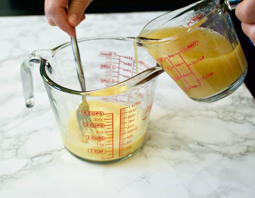 pouring broth into a measuring cup of whisked eggs