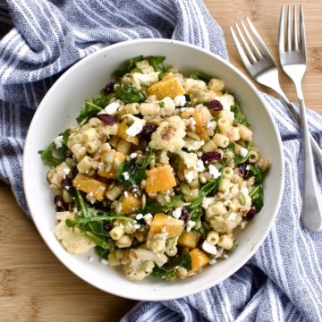 Winter pasta salad in a white bowl on towel next to two forks